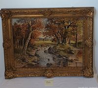Full view of the framed oil painting showing a landscape with a flowing stream, autumn colored trees, and detailed ornate gold frame.