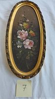 Full view of the oval framed 20th century oil on canvas still life flower painting with a dark background and detailed pink and yellow flowers.