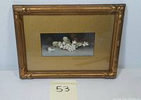 Image of framed watercolor painting showing white flowers and green leaves on a dark background