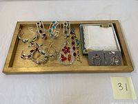 Full view of wooden tray holding seven silver bracelets with colored stones, Irish linen handkerchiefs in box, and two silver Christmas ornaments.