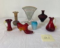 Photo showing all seven hand blown colored glass items arranged on a white surface including vases of various sizes and a lizard figurine.