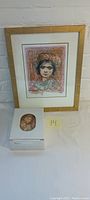 Framed signed lithograph portrait by Edna Hibel alongside the white vanity box with floral image on lid.