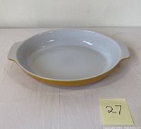 Top view of oval enamel serving dish showing white interior and yellow exterior with handles