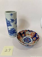 Photo showing the tall blue and white pictorial Japanese porcelain vase and the colorful Imari porcelain bowl side by side on a white background.