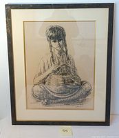 Framed lithograph of young girl sitting cross-legged with basket in lap