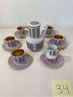Photo showing teapot in the center with six cups and saucers arranged around, highlighting the gold interior of cups.