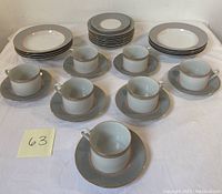 Overview of the full set including bowls, dinner plates, tea cups and saucers on a white tablecloth.