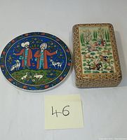 Photo showing the top view of the rectangular Persian vanity box alongside the round tile trivet, highlighting the detailed hand-painted scenes and colorful designs.