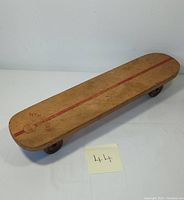 Full view of the vintage wooden skateboard showing red stripe and Sears Wipe Out branding.