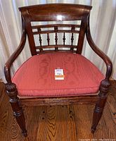 Front view of the chair with pink seat cushion highlighting carved arm rests, turned legs, and curved backrest with spindle design.