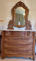 Front view of antique wooden dresser with marbled top and attached mirror