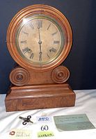 Full front view of wooden Grecian style shelf clock with antique dial, winding key, and note on dimensions and movement.