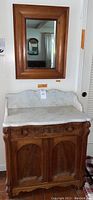 Full view of the antique wash stand with white marble top and wood-framed mirror above it, showing overall form and finish.