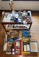 Photo of wooden rolling cart with art and office supplies on and around it.
