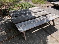Photo showing two weathered wooden benches with angled legs placed outdoors on a stone patio, each with different width dimensions shown by size comparison.