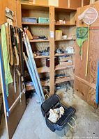 Corner shelving with leaning fishing rods, nets and tackle boxes