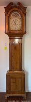 Full front view of the wooden grandfather clock showing entire tall case and hood