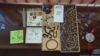 Wide view of assorted bracelets, necklaces, earrings, perfume bottle, and stones,
