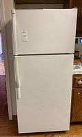 Closed white Kenmore top freezer refrigerator showing front exterior and handle.