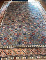 Top view of entire rectangular area rug showing geometric floral pattern and border