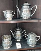 Five Victorian era silverplate tea service pieces including two teapots, creamer, large sugar bowl, and loving cup, all marked 1974.