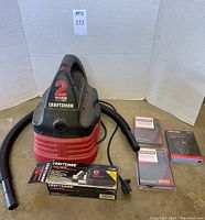 Craftsman 2 gallon wet/dry shop vac with hose, nozzle attachments, filter packs, and boxed accessory kit arranged on floor.
