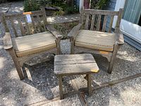 Front view of two wooden captain's chairs with striped cushions and slatted side table