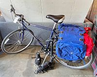 Purple-blue Specialized Crossroads bicycle leaning on sofa with rear rack and blue and red panniers