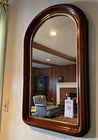 Full front view of mirror hung on wall showing arched shape and frame