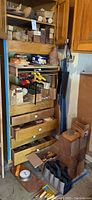 Wide view of shelving unit filled with various sizes and shapes of wood blocks, clamps on a shelf, and drawers likely containing tools