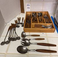 Overview of bamboo organizer filled with flatware pieces and loose utensils on countertop