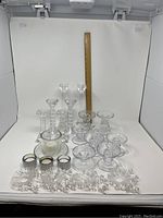 Overall lot of crystal and glass candlesticks with some plastic bobeches, shown beside a wooden ruler for scale