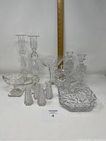 Clear crystal collection including paired candlesticks, salt and pepper shakers, square candy dish with chip, jam pot and large Victorian style open salt dish, shown with ruler for scale.