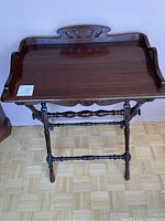 Front angled view of antique walnut butler stand showing tray top with gallery edge and turned legs with stretchers.