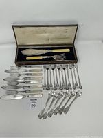 Photo showing entire flatware lot including ivory-handled fish servers in box, mother of pearl fish knives and forks, silver plated seafood and escargot forks.