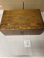 Top exterior view of oak cutlery chest with inset brass plaque visible on the lid.