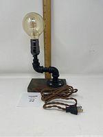 Front view of the industrial pipe table lamp on a pine base with cloth-covered wire and Edison bulb; ruler shows the height.