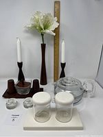 Wide view showing all items including teak condiment set with tray, teak candle holders, tall teak vase, Pyrex teapot, Scandinavian glass candle holders, plastic cream and sugar set.