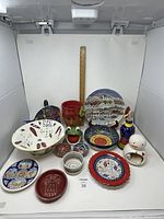 Photo of all the pottery items including colander, vase, plates, and decorative bowls arranged on white background with measuring ruler for scale.