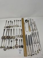 Overview of entire flatware and spoon set arranged by type with ruler for scale