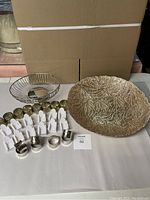 Photo of the large glass low bowl, wire metal bread basket, and white plastic Adirondack chair-shaped place card holders with metal napkin rings in front