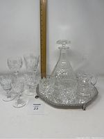 Full lot view showing decanter, Waterford glasses, unmarked glasses, and silver plated salver with measuring ruler.