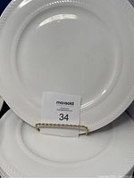 Close-up of one white dinner plate showing embossed rope pattern rim and size indication