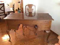 Full view of wooden desk with cabriole legs and scalloped apron