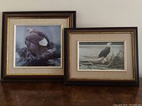 Two framed prints side by side on wood table showing bald eagles by Robert Bateman.