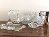 Lot of crystal items on wood table, showing various vases and dishes with etched designs