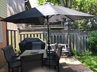 Overall view of rectangular tile-top table, six sling chairs, black umbrella and cast iron base