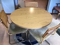 Three cane-back chairs arranged around round laminate tabletop