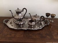 Full view of entire tea set arranged on tray showing all components including both pots, sugar bowl, creamer, tray, and goblets.