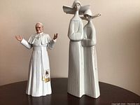 Front view of Royal Doulton Pope John Paul II figurine and Lladro figurine of two women